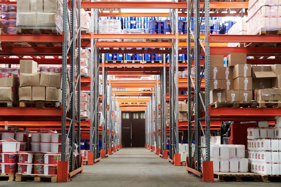 Magazijn met oranje stellingen vol dozen en pallets